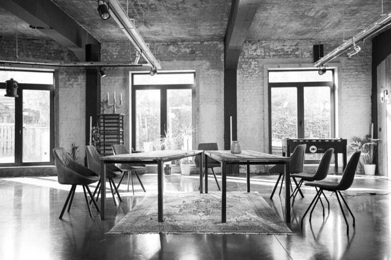 Le Loft Roots avec tables sur tapis et grandes fenêtres